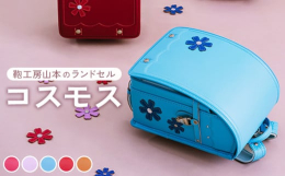 コスモスのモチーフと波型のステッチで、上品な可愛らしさを表現。幸せを運ぶクローバーやお花のカシメなど、細かな部分にも可愛らしさを詰め込みました。素材を仕入れ、市内工房で裁断縫製加工、梱包を行っているこ